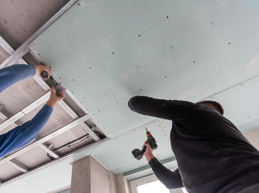 Drywall board being fixed to an interior ceiling frame