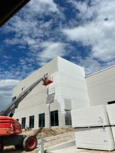 Painters operating a boom lift for a commercial warehouse exterior painting project