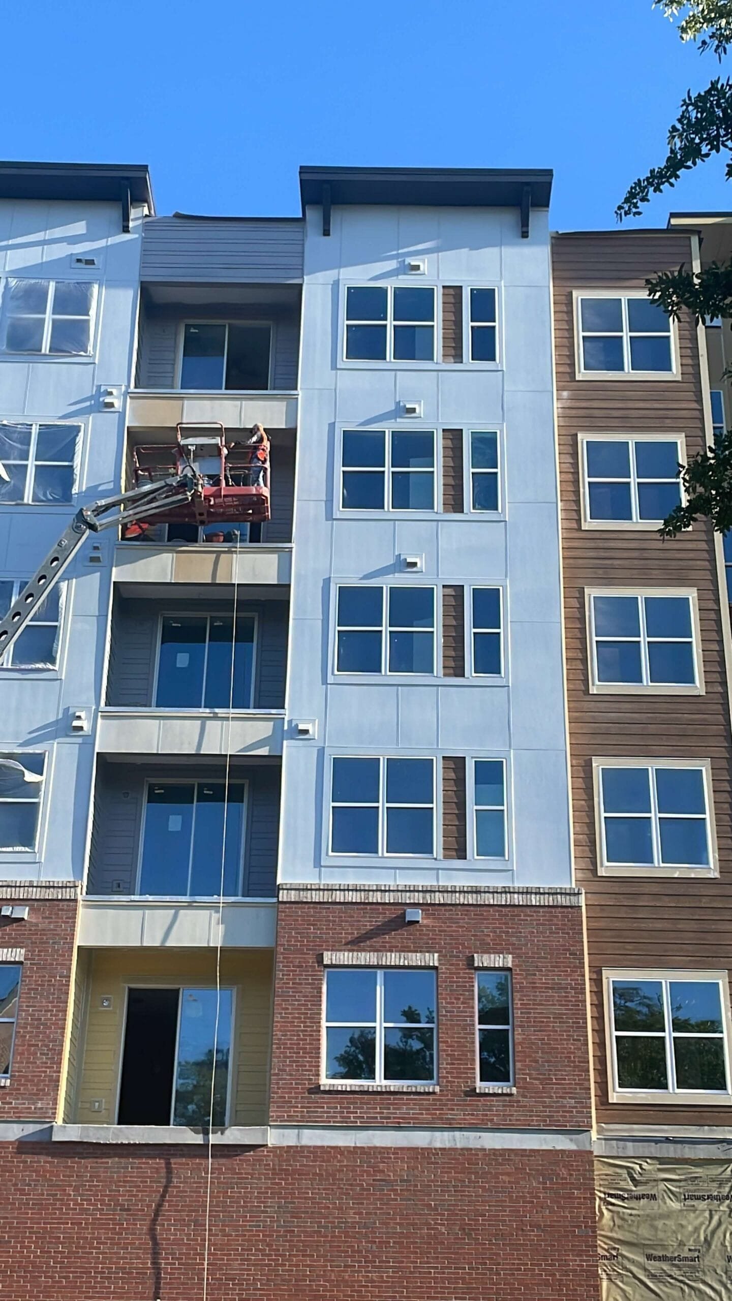 Safety equipment, including boom lift, in use at a residential exterior painting site, protected windows