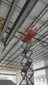 Painters operating a scissor lift for a commercial warehouse interior painting project