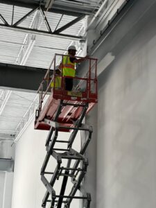 Safety equipment, including scissor lift, in use at a commercial interior painting site