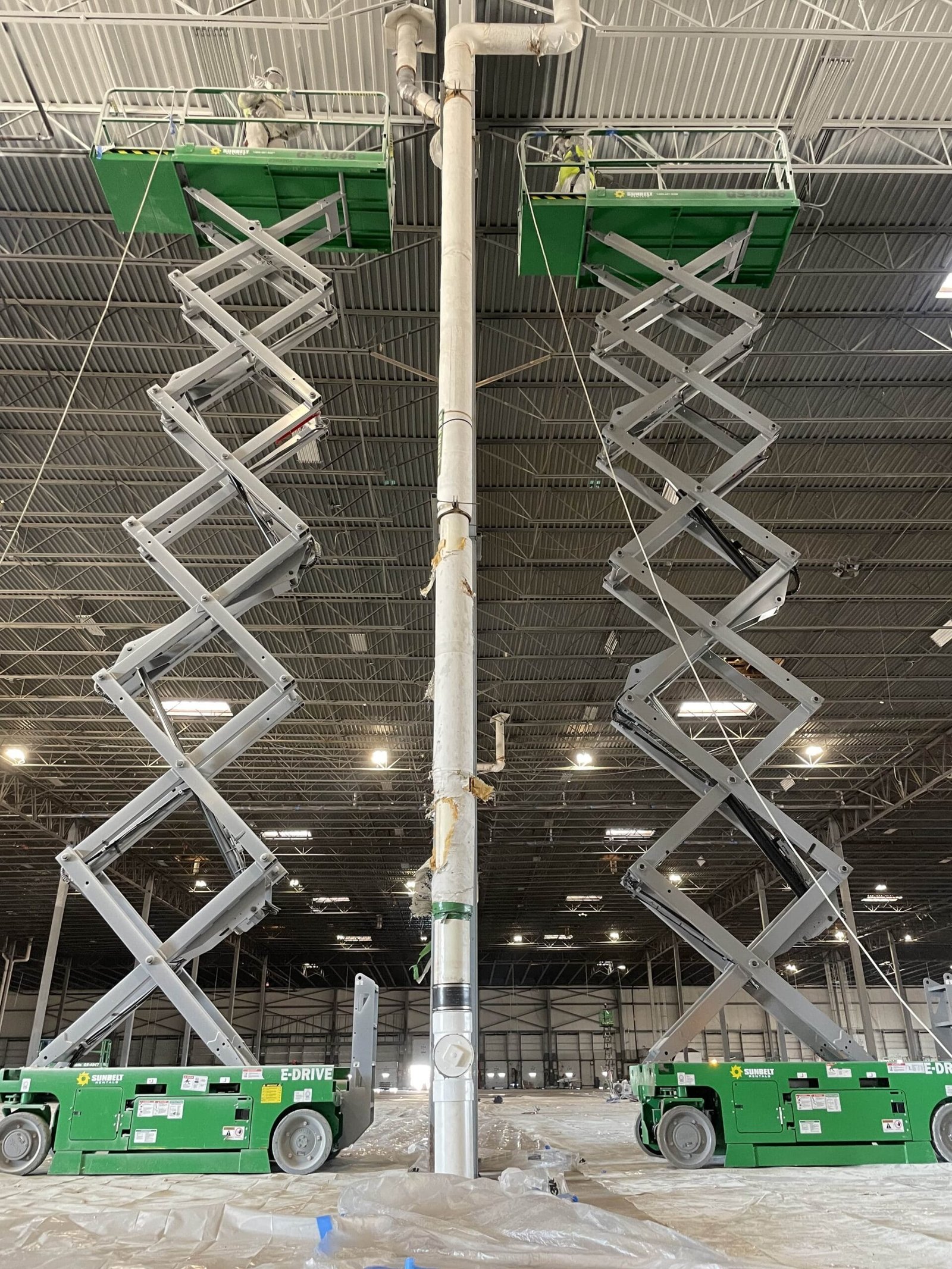 Painting crew working on large commercial building interior with scissors lift